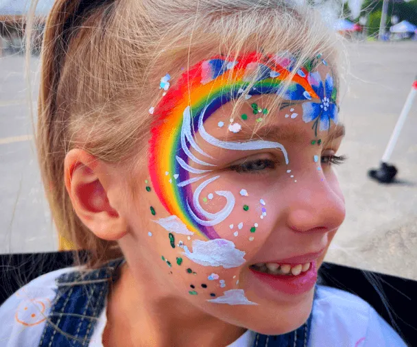 A child with a rainbow painted on their face.