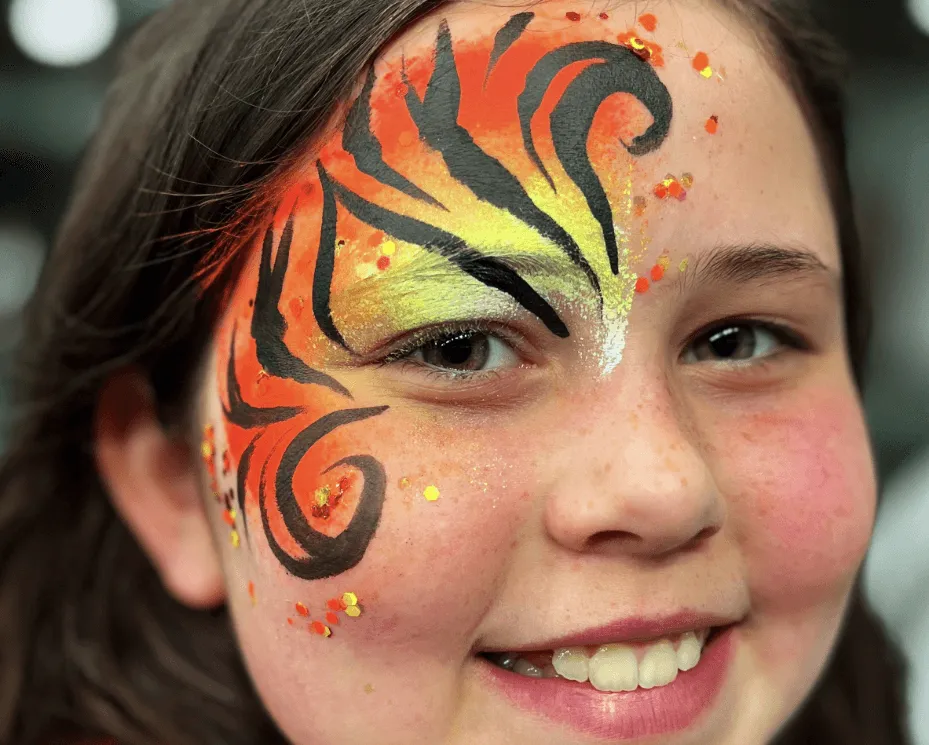 A kid proudly displaying an amazing facepaint artwork